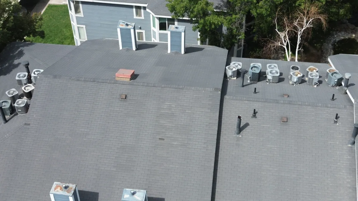 A missing roof cricket leading to water pooling and debris buildup behind a large chimney